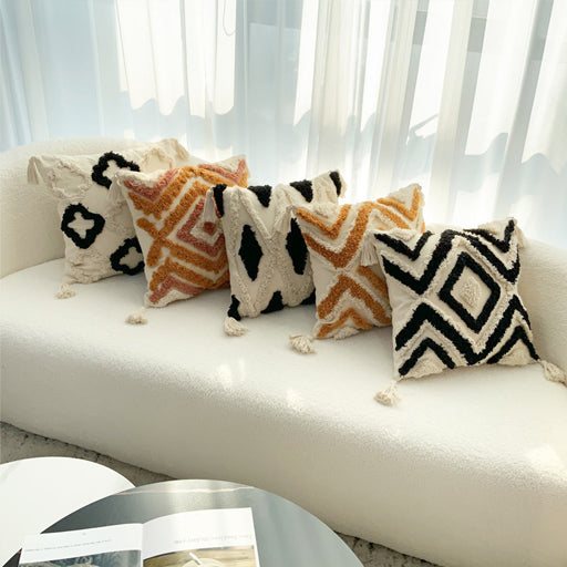 Decorative pillows with geometric patterns on a white sofa in a bright room.