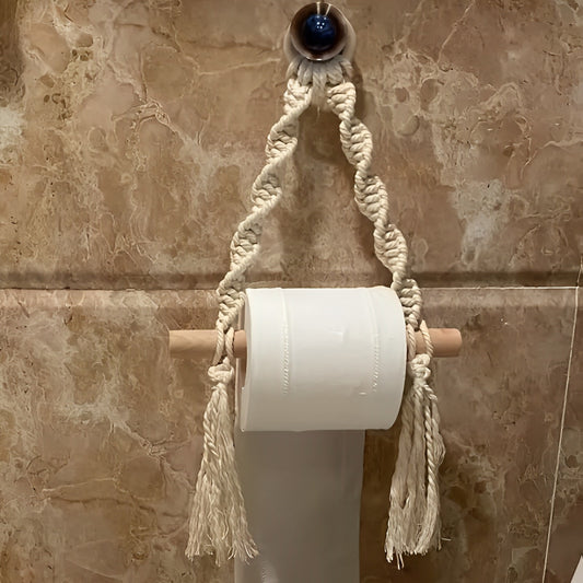 Macrame toilet paper holder with a roll of toilet paper on a marble wall.