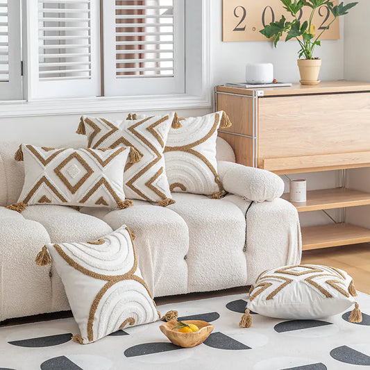 Decorative pillows on a beige sofa in a living room setting with a wooden cabinet and plant.