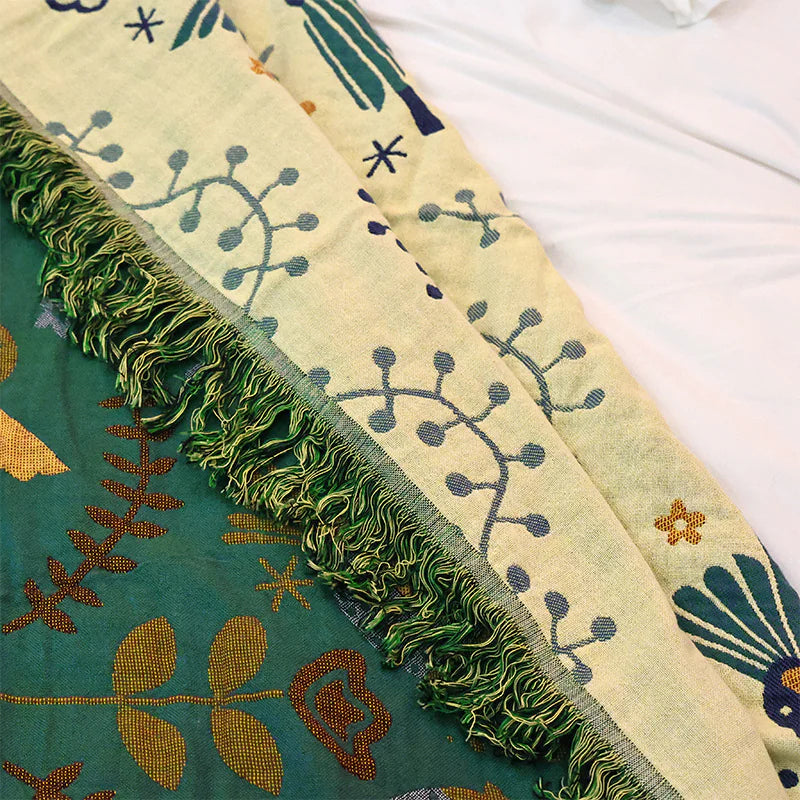 Close-up of a fabric with green fringes and embroidered patterns on a white background
