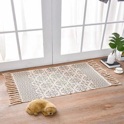 Decorative rug with tassels on a wooden floor in a bright room.