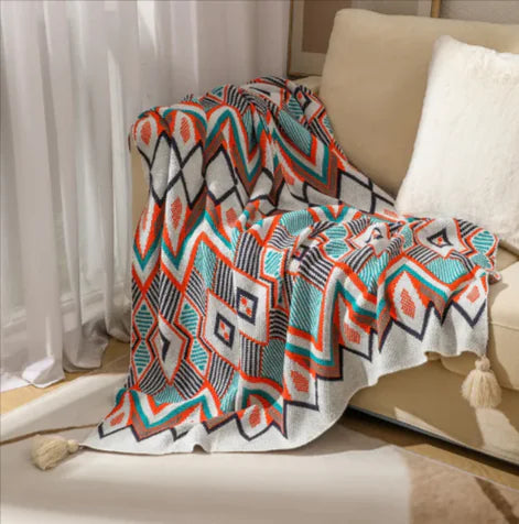 Colorful patterned blanket draped over a couch in a living room setting.