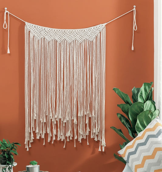 String art hanging on a wall with plants and a pillow in the foreground