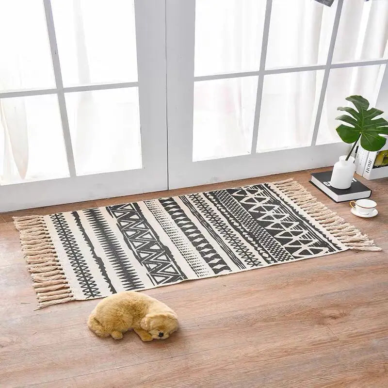 Patterned rug on a wooden floor with a small plush toy in front of a large window.
