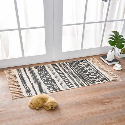 Patterned rug on a wooden floor with a small plush toy in front of a large window.