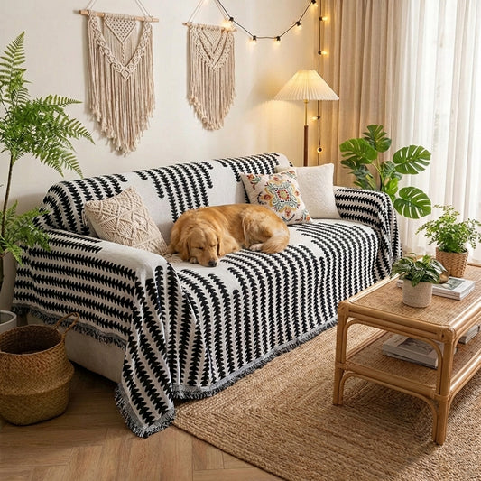 Dog lying on a black and white patterned blanket on a couch in a cozy living room.
