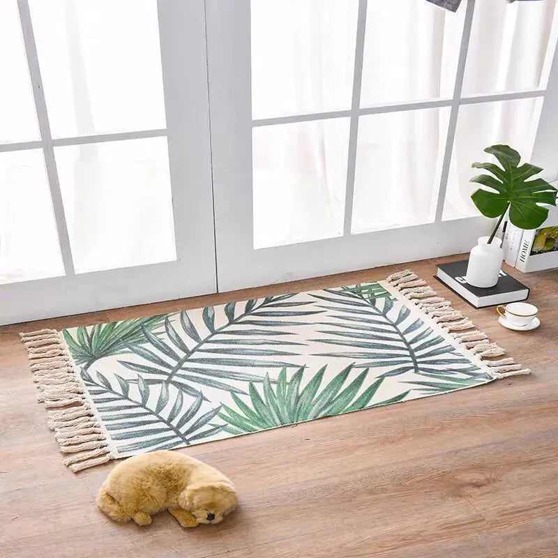 Green leaf-patterned rug on a wooden floor with a small plush toy and plant in the background.