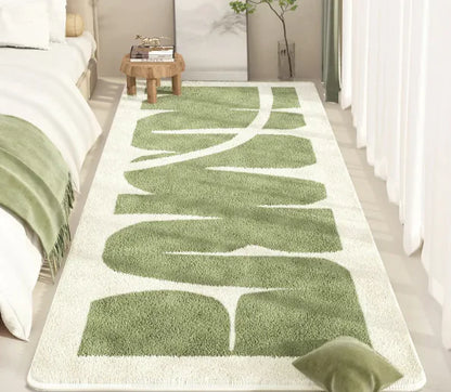 Green and white patterned rug on a wooden floor in a bedroom setting.