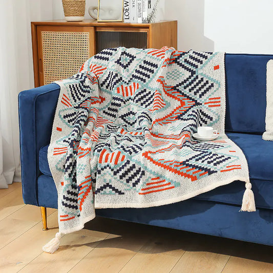 Patterned blanket draped over a blue sofa with a wooden sideboard in the background