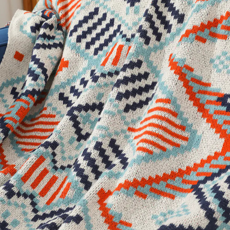 Close-up of a knitted blanket with geometric pattern in blue, orange, and white.