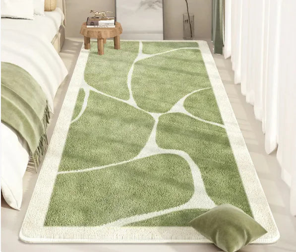 Green leaf-patterned rug on a light wooden floor next to a bed.