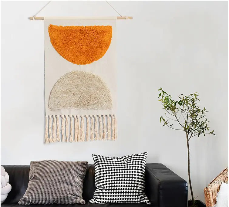 Woven wall art with orange and beige design hanging above a sofa with decorative pillows.