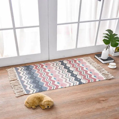 Patterned rug with tassels on a wooden floor in a room with large windows.