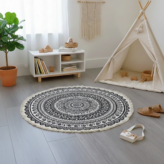 Round black and white patterned rug on a wooden floor with a child's play area in the background.