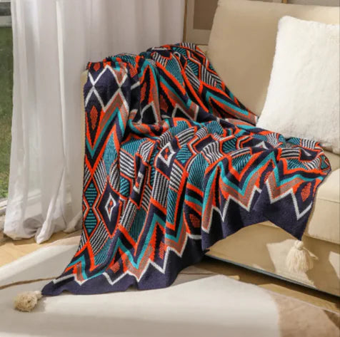 Colorful patterned blanket draped over a couch with a neutral background
