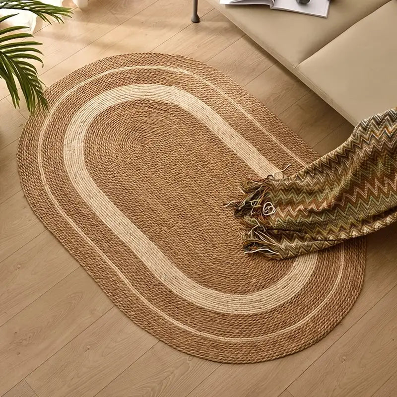 Round braided rug on a wooden floor with a patterned throw blanket.